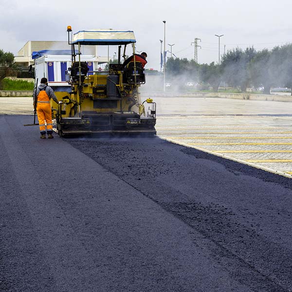 Asphalt paver with asphalt heated to temperatures above 160 ° during road at the construction. Road specialized equipment is laying the way.