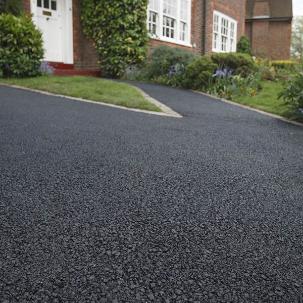 New asphalt tarmacadam driveway outside a beautiful brick house in London. Lots of copy space