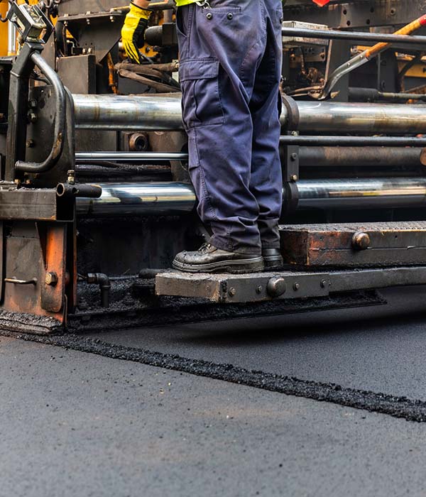 Close-up of Asphalt paving machine and road construction crew resurfacing suburban road with a new layer of asphalt.