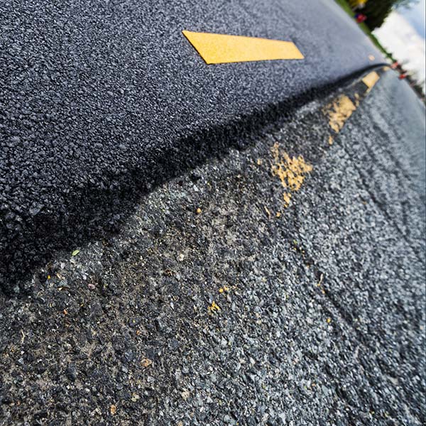Old verses new look at a resurfaced lanes of a worn road compared to newly installed asphalt, The old road surface is worn, cracked and crumbling, the yellow lines are barely visible, compared to the newly laid asphalt