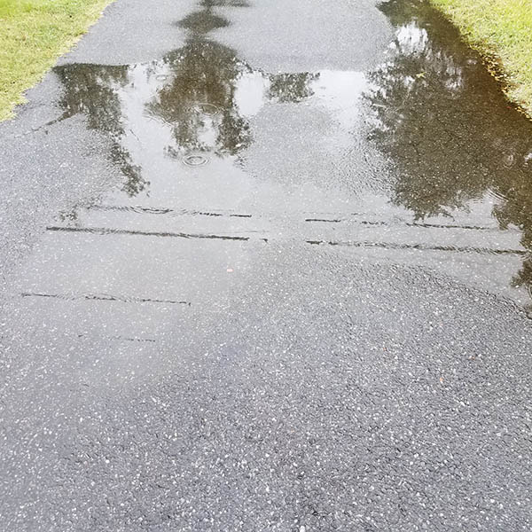 an asphalt driveway with large water puddles from rain