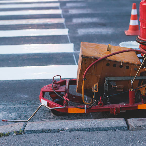 Process of making new road surface markings with a line striping machine, workers improve city infrastructure, demarcation marking of pedestrian crossing with a hot melted paint on asphalt pavement