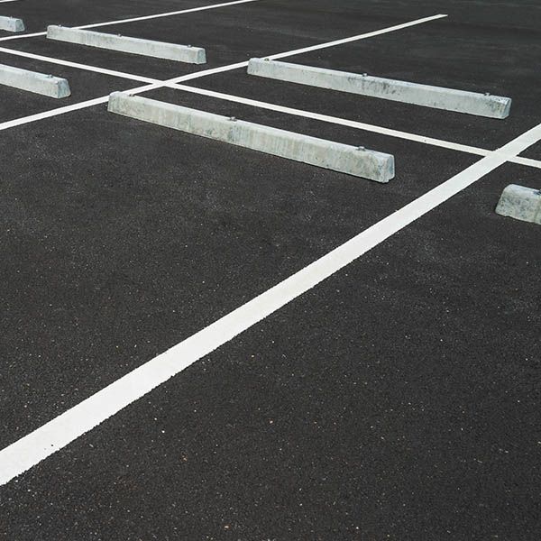 Empty space outdoor asphalt car parking lot (white line and concrete wheel stopper). Traffic and transportation concept.